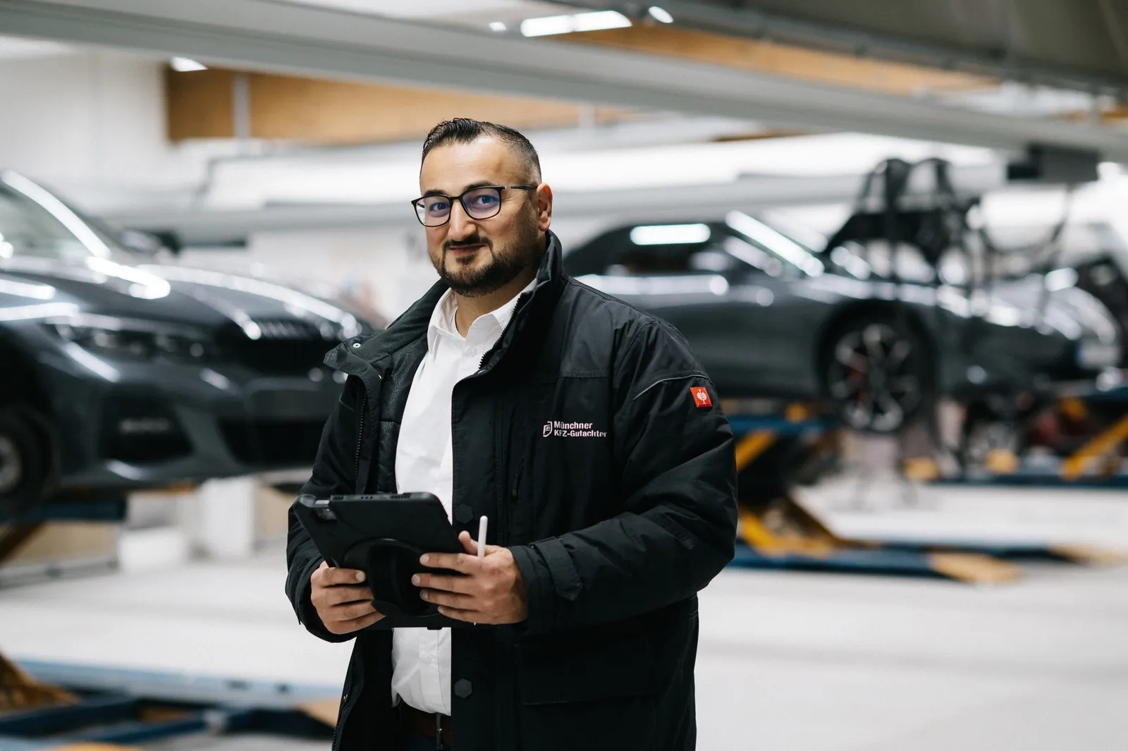 KFZ-Gutachten München – Bewertung durch Sachverständige Cüneyt Kadak, Kfz-Sachverständiger in München, mit Tablet in der Werkstatt